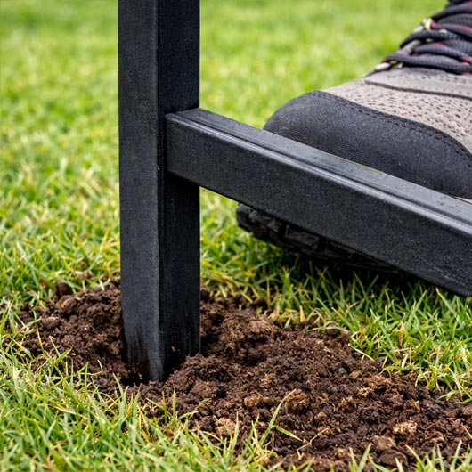 Close-up of metal frame lawn sign stake being pushed into the ground with a foot on the horizontal bar for easy installation