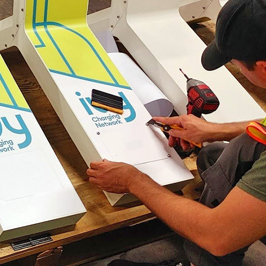 Professional custom vinyl wrap installation on EV charging station panels with precision graphic application in Toronto GTA