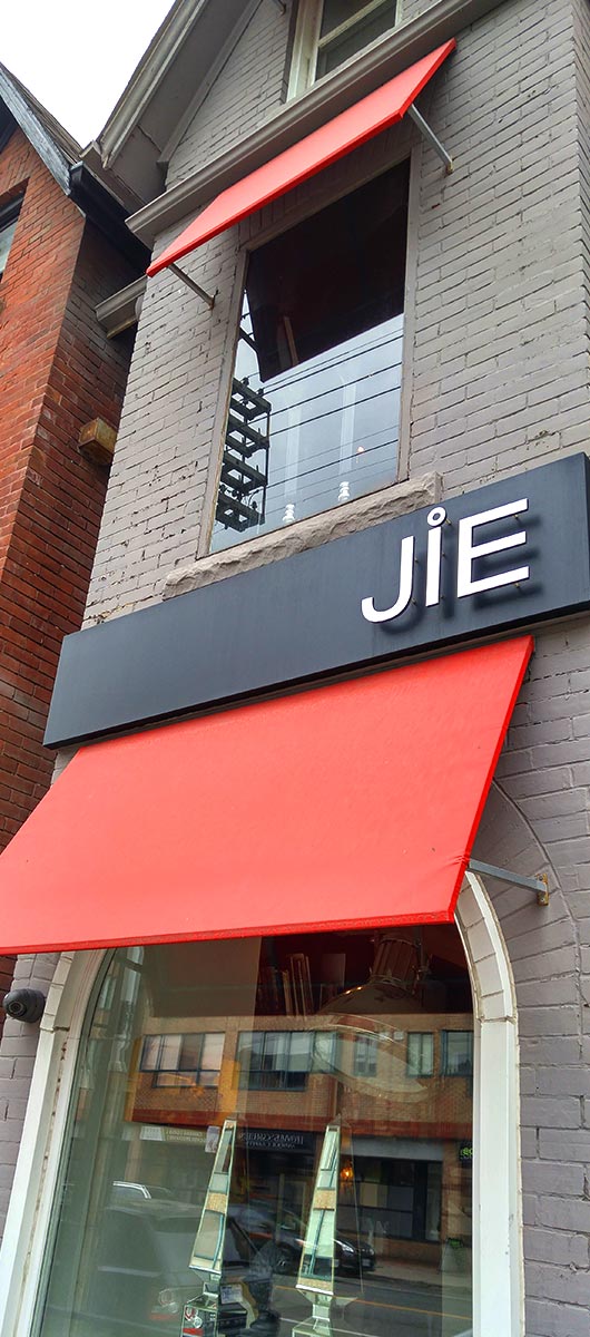 Red custom storefront awnings installed above retail shop windows