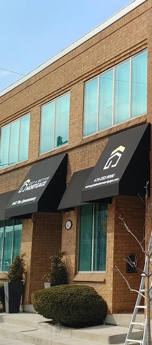 Black custom storefront awnings with printed logos installed on commercial building windows