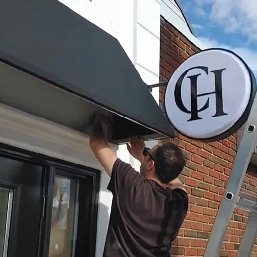 Installing custom fabric storefront awning above retail shop entrance